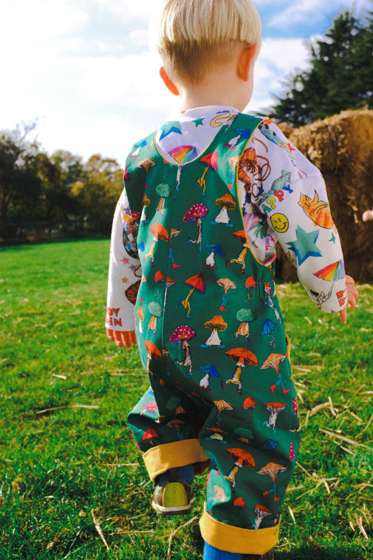 Child wearing a colorful outfit with nature-themed design in an outdoor setting